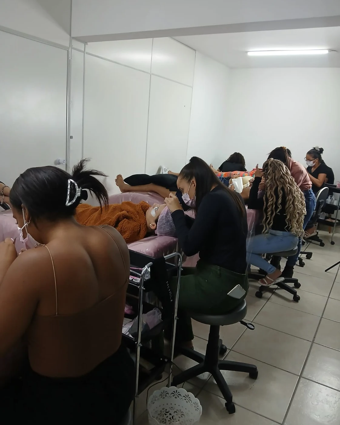 Alunas atendendo modelos reais em aula prática de extensão de cílios